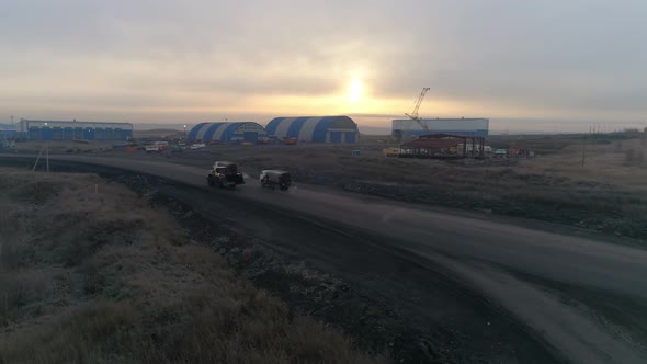 Aerial view of large trucks and a tractor drive through the industrial area 01