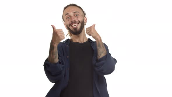 Cheerful Hipster Guy with Beard Tattoos on Face and Body Jumping From Bottom and Showing Thumbsup