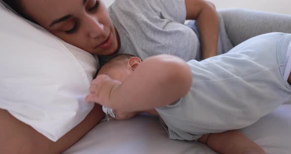 Young loving mother lying with her son on bed at home - Family and motherhood concept