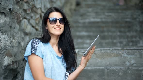 Young Woman Tourist is Reading Interesting Historical Facts on Touch Pad During a Tour in the Old