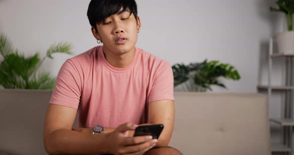 Bored man using smartphone sitting on couch at home