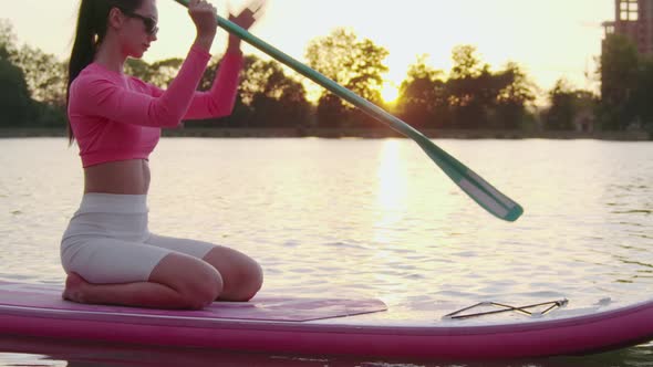 Sporty Woman Swimming on Paddle Board on City Lake