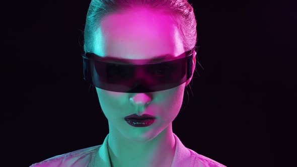 Portrait of teenage girl in cyberpunk style. Young woman posing in futuristic sunglasses.