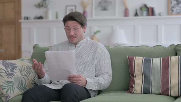 Man Celebrating Success on Document on Sofa