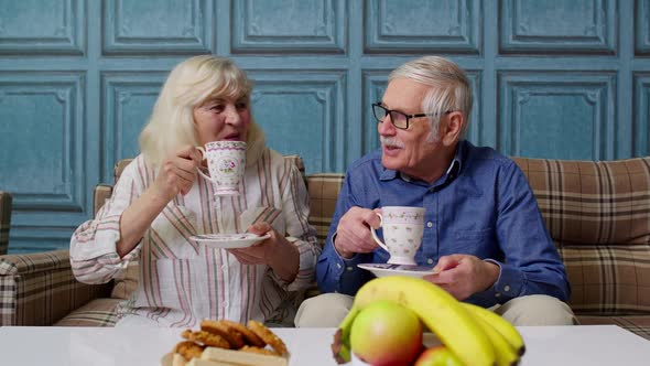 Mature Family Couple Grandfather Grandmother Relaxing on Cozy Sofa Enjoying Conversation at Home