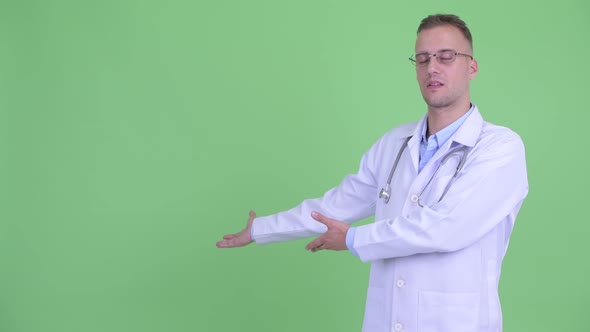 Happy Handsome Man Doctor Talking While Showing To the Back