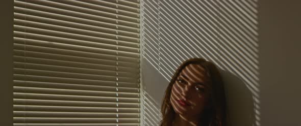 Woman peeking out through blinds