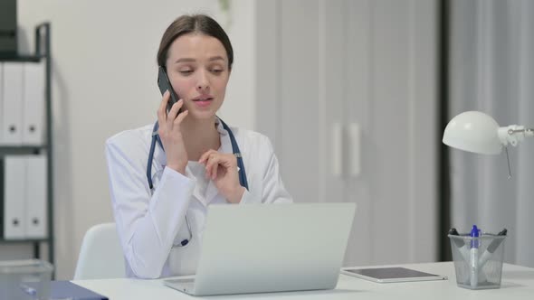 Female Doctor with Laptop Talking on Smartphone 