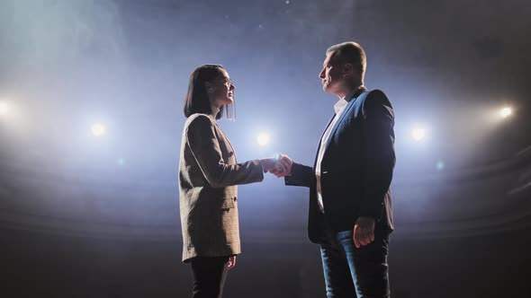 Politicians Shake Hands After Debate. The Action Takes Place on Stage, Spotlights Shine on the