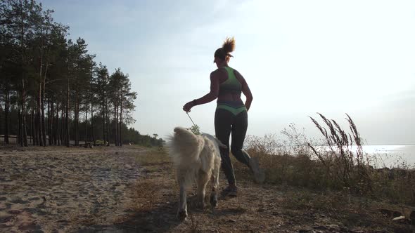 Athletic Woman Running Along Coastline with Dog