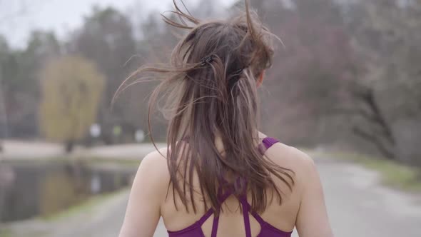 Young Healthy Caucasian Woman Jogging in Park on Lake Shore