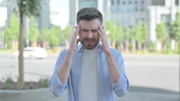 Outdoor Portrait of Young Man Having Headache