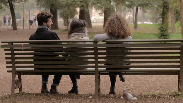 betrayal, cheating.Three people on the bench man flirting with both women