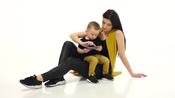 Mom and Child Are Watching Cartoons on a Smartphone, White Background