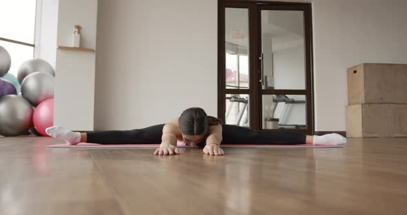 Athletic Woman Stretching on a Mat in a Fitness Studio