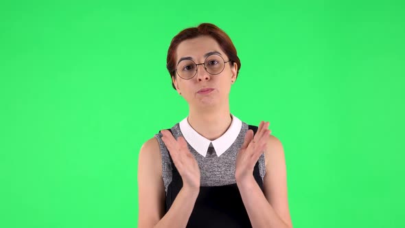 Portrait of Funny Girl in Round Glasses Is Clapping Her Hands Indifferent. Green Screen