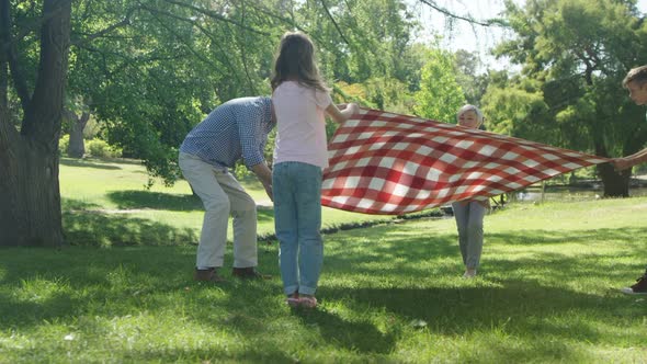 Multi-generation family placing blanket in the park