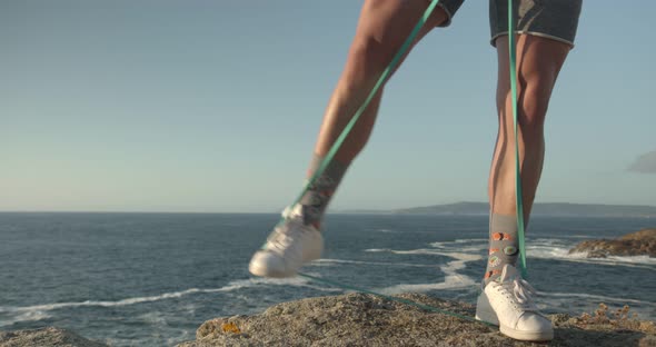 Anonymous athletic man training with elastic band with the foots