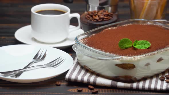 Tiramisu Dessert in Glass Baking Dish and Cup of Fresh Hot Espresso Coffee on Wooden Background