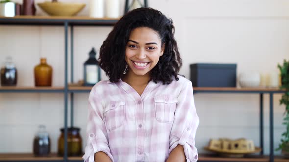 Happy black woman sitting at home and smiling at camera