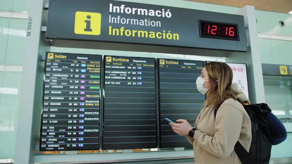 Female Traveller Wearing Medical Face Mask Hand Use Smartphone Checking Flight Schedule Standing