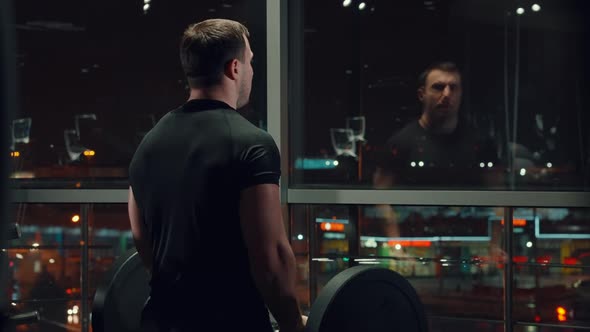 Man Exercising with Barbell Near Window