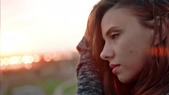 Close Up Face of Young Pensive Woman Melancholically Looking at Amazing Sunset and Touching Hair