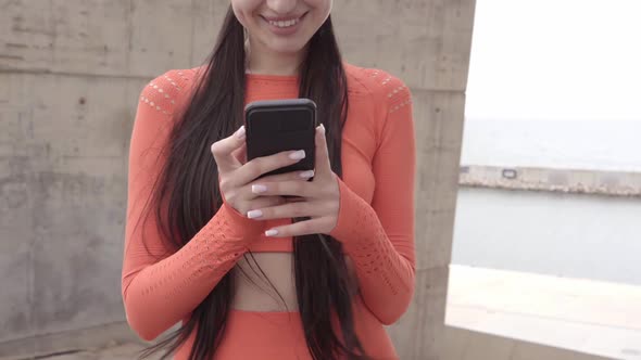 Close Up Smiling Woman in Sportswear Using Phone Outdoors