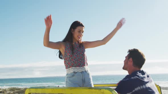 Caucasian couple sitting in beach buggy by the sea talking and dancing