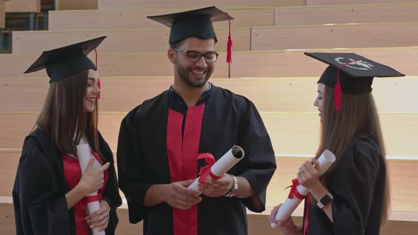 Graduates in Robes Holding Certificates, Talking.