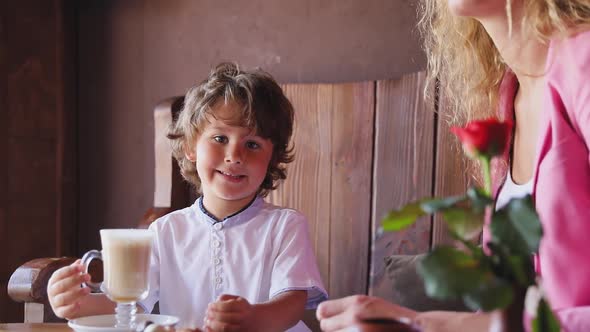 Little Boy With Cup Of Cacao At Cafe