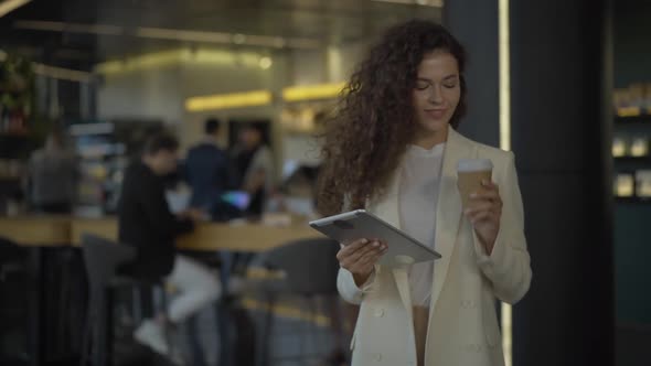 Portrait of Successful Young Businesswoman Posing with Tablet and Coffee Cup. Smiling Beautiful