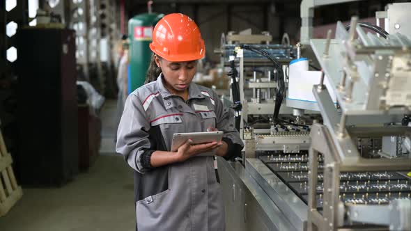 A young black manufacturing worker controls an assembly line in a factory