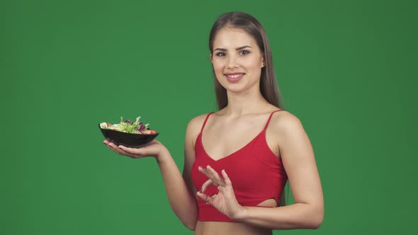 Happy Young Fit Woman Showing Ok Sign Smiling Holding a Bowl of Fresh Salad