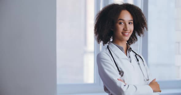 Young African Confident Doctor Nurse Wears Medical Uniform, Stands Looks Friendly, Approvingly Shows