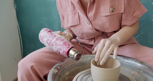 Female Potter Sitting and Makes a Cup on the Pottery Wheel. Woman Making Ceramic Item. Pottery