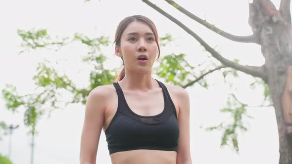 Asian young sport woman take deep breath before running for health care in public park.