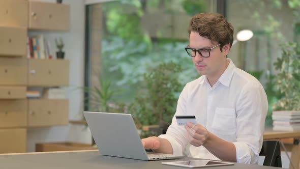 Young Man Making Online Payment Failure on Laptop in Modern Office