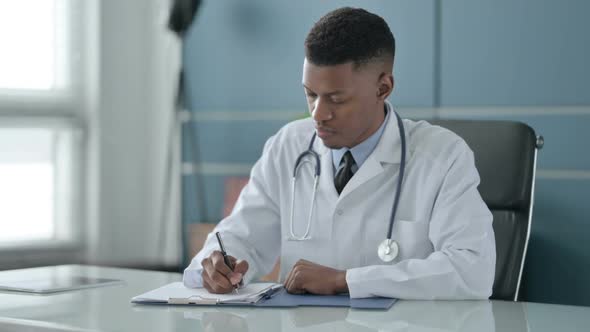 African Doctor Writing on Paper in Office