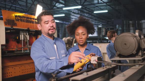 Two professional engineers inspect machines' electric systems at the factory.