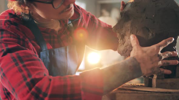 A Man is Sculpturing a Head From Clay