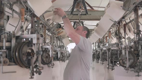 Worker working at a circular knitting machine in knitting factory