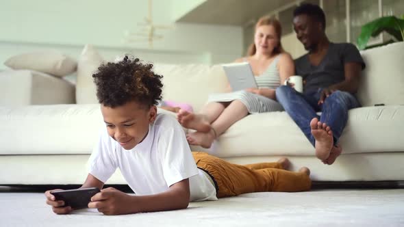 Multiethnic Family Using Devices and Having Good Time Together in Apartment Room Spbd