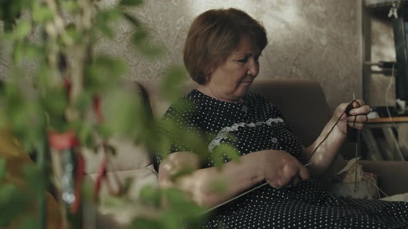 Mature woman knitting at home 