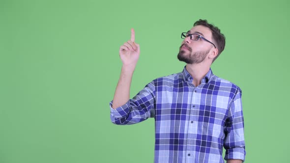 Happy Young Bearded Hipster Man Talking While Pointing Up