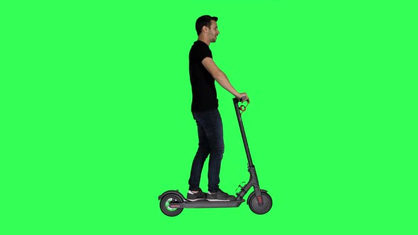 Riding an Electric Scooter by A Casual Looking Young Man.Turns Left and Right Over a Green Screen