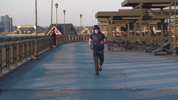 Young Sportive Man Jogging on the Quay