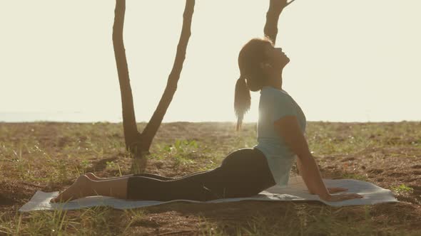 Asian cute girl She is doing yoga in the morning in the garden by the beach.