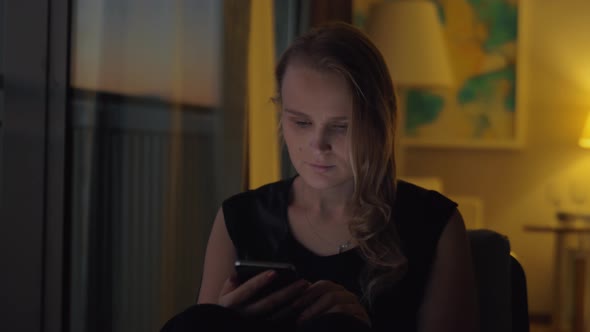 Woman with a Smartphone in Cozy Evening Interior