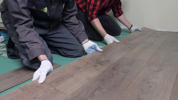 Two Workers are Laying Laminate Flooring in a Small Apartment